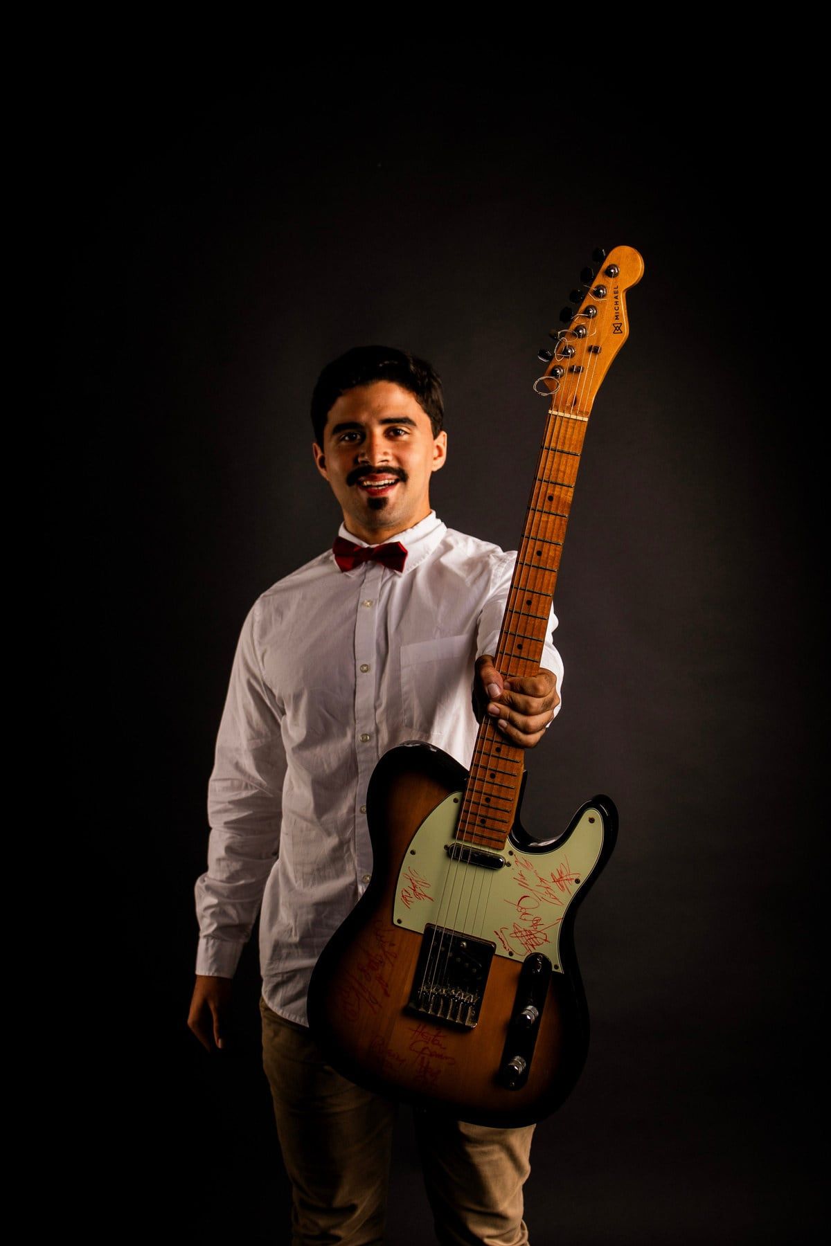 Guitarrista de gravata-borboleta em cena escura