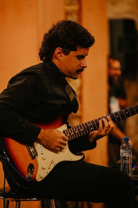 Guitarrista tocando em apresentação de jazz em ambiente de luz quente