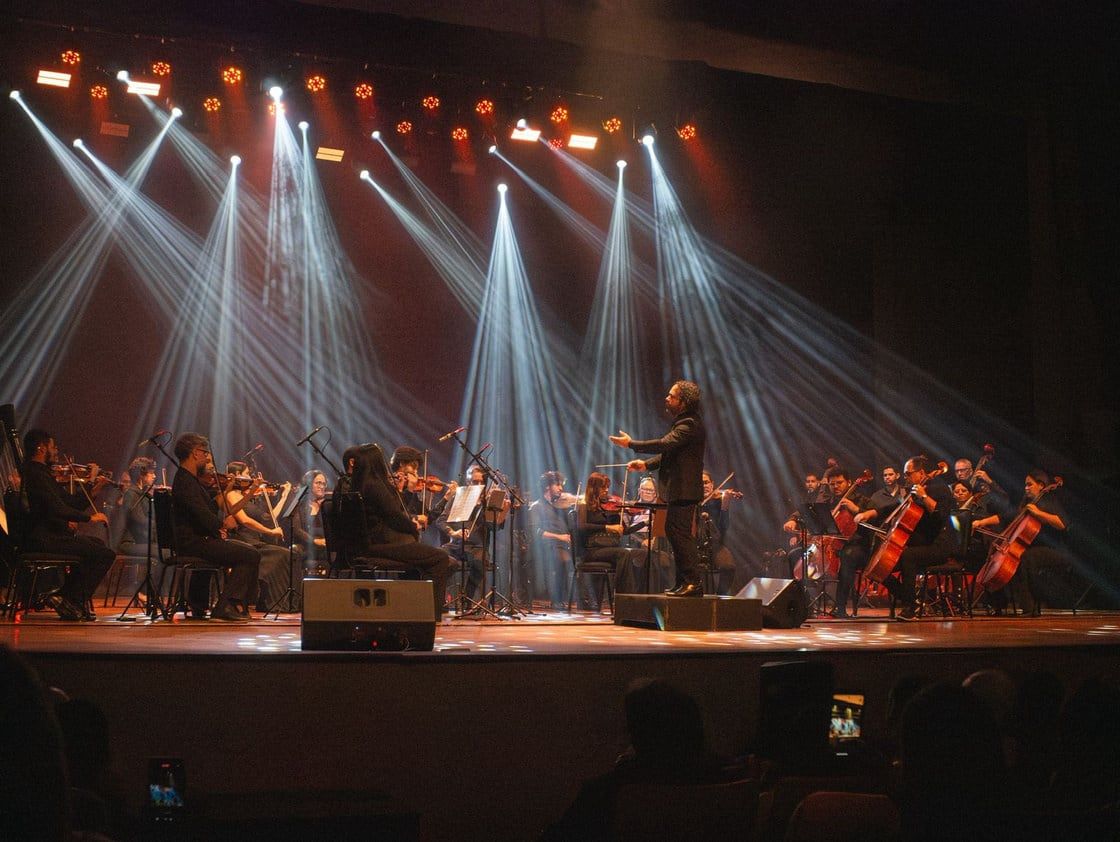 Orquestra Filarmônica de Alagoas em palco iluminado