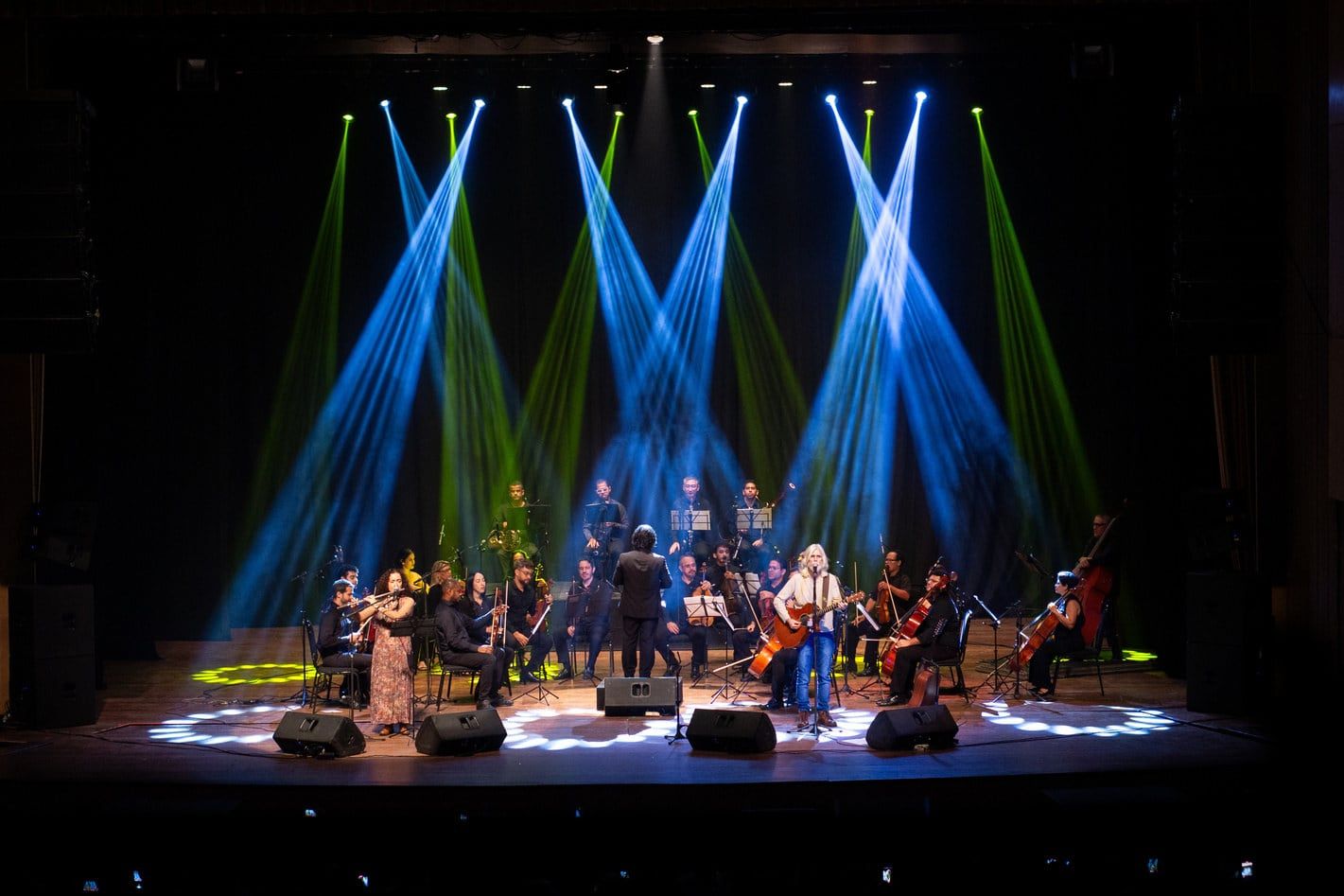 Orquestra e solistas sob feixes de luz colorida