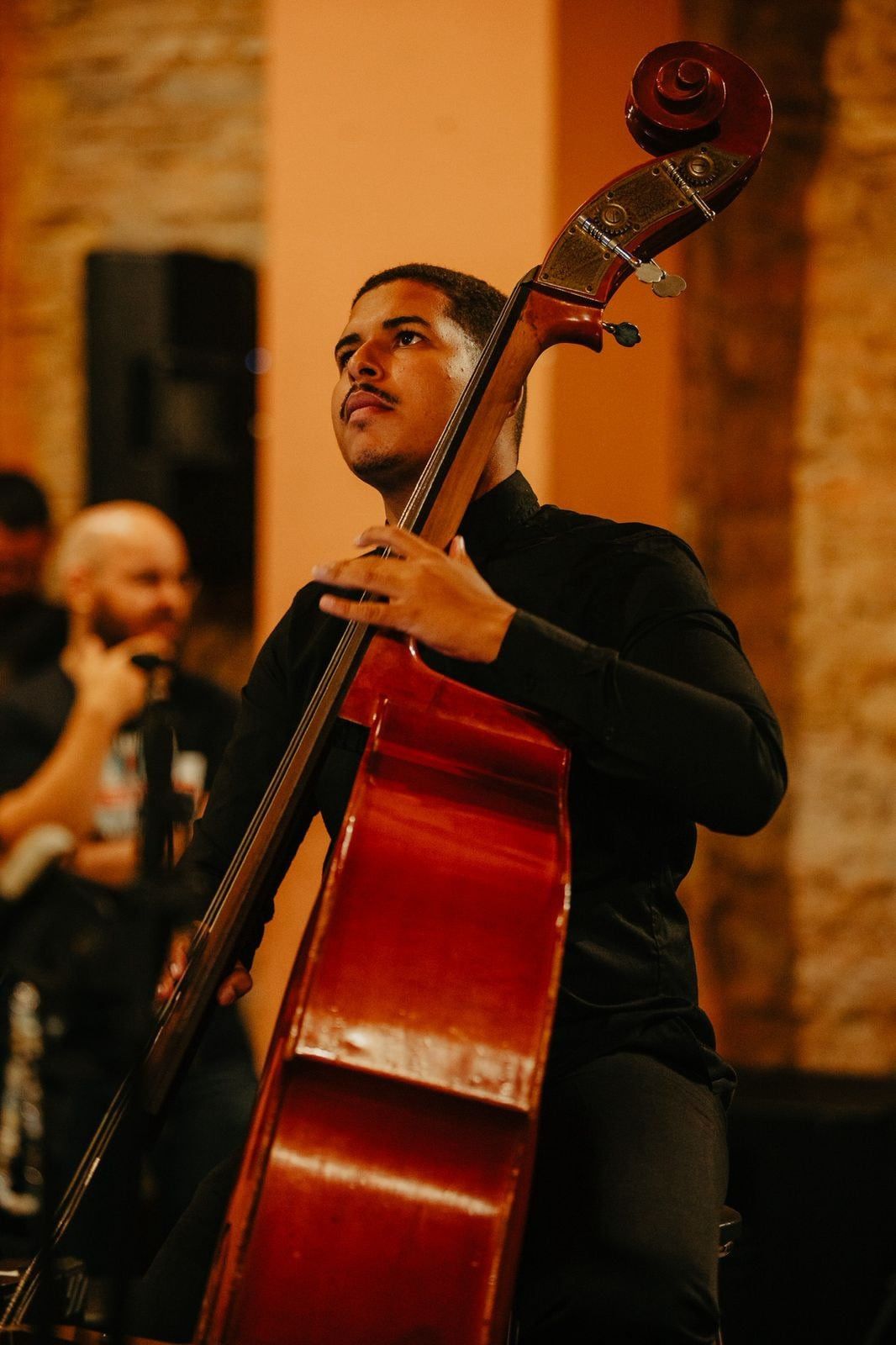 Luiz Guilherme tocando contrabaixo em ambiente de luz quente